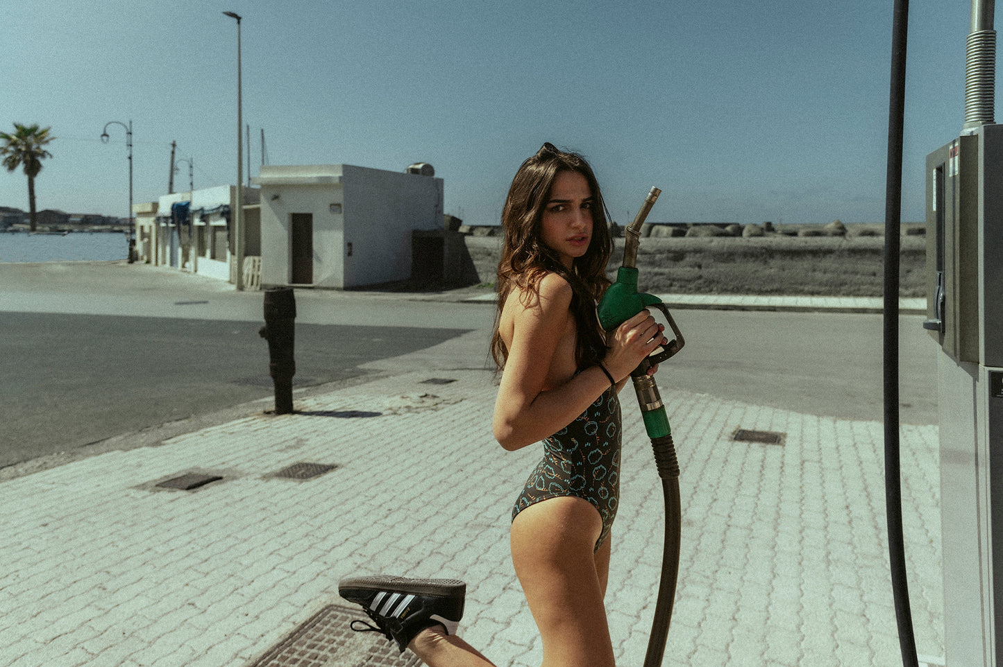 girl wearing black costume swimsuit called jill with cloud texture and a shoe at the gas station