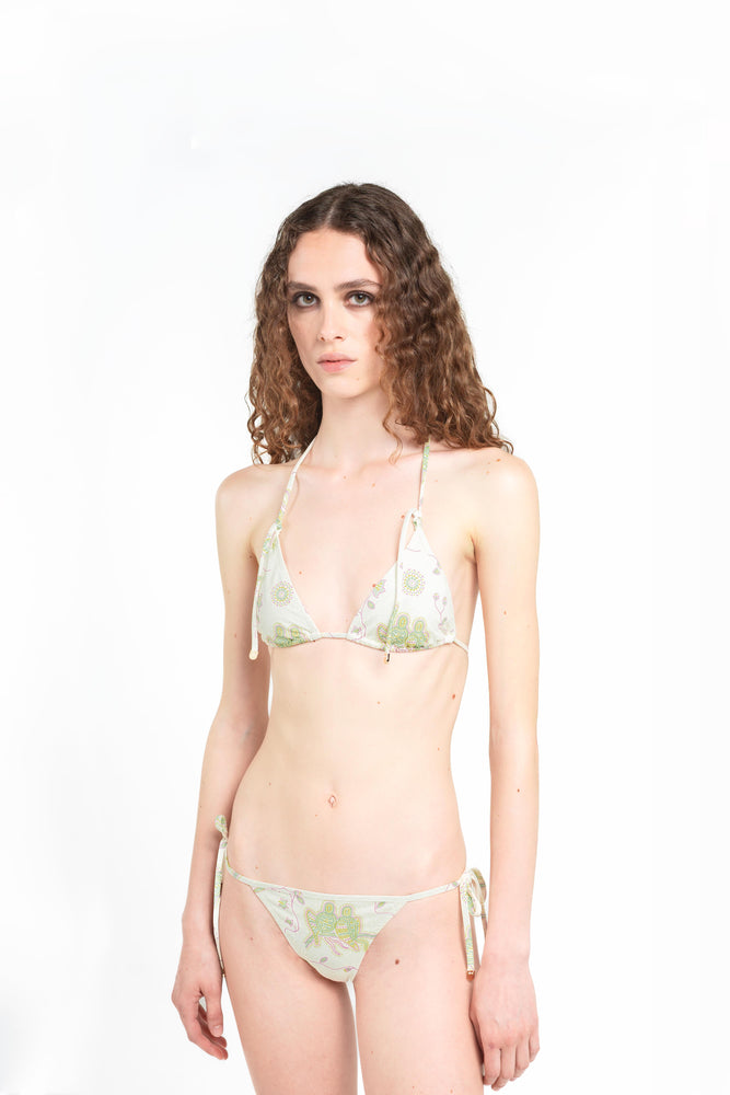 piano americano di modella su sfondo bianco che indossa il bikini Noodle Beachwear Ellie di colore bianco latte con stampa di pappagalli a mosaico dalla collezione estiva del 2025 Noodle Mirage
american cut of model wearing a white printed parrots Ellie bikini of Noodle Beachwear from the 2025 Noodle Mirage Collection