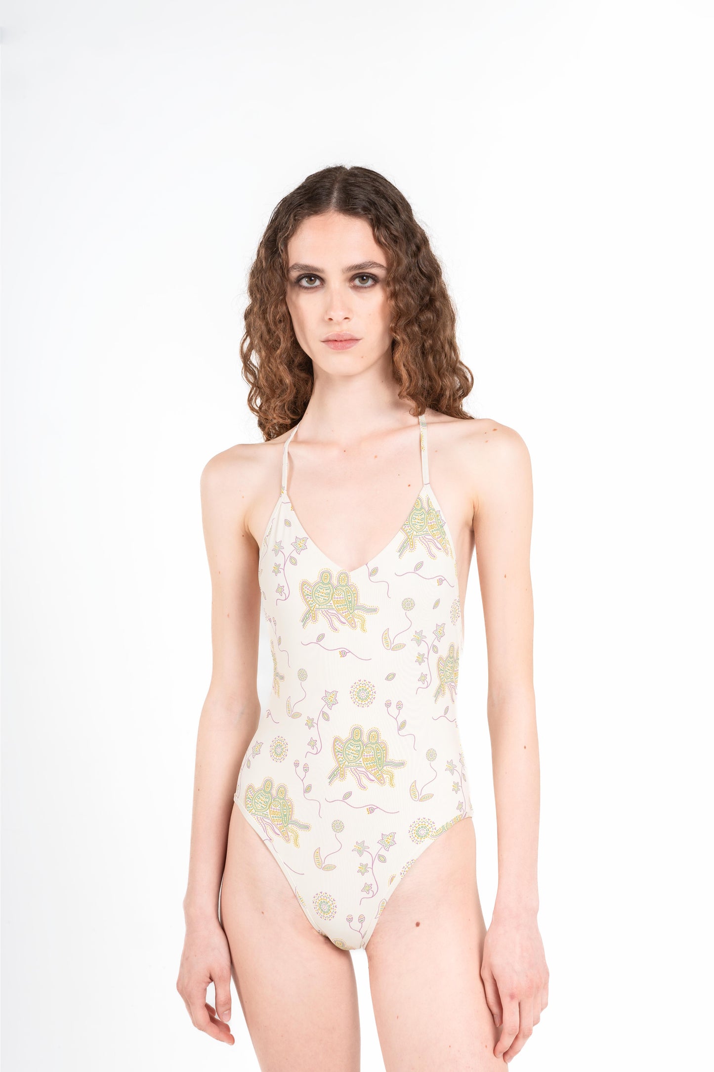 donna indossa costume intero jill di colore latte bianco con stampa a mosaico di pappagalli verdi gialli e viola con sole e fiori onirici dalla collezione nuova 2025 noodle mirage estiva di Noodle Beachwear

woman wears Jill one-piece swimsuit in milk white with mosaic print of green yellow and purple parrots with dreamlike sun and flowers from the new 2025 noodle mirage summer collection by Noodle Beachwear