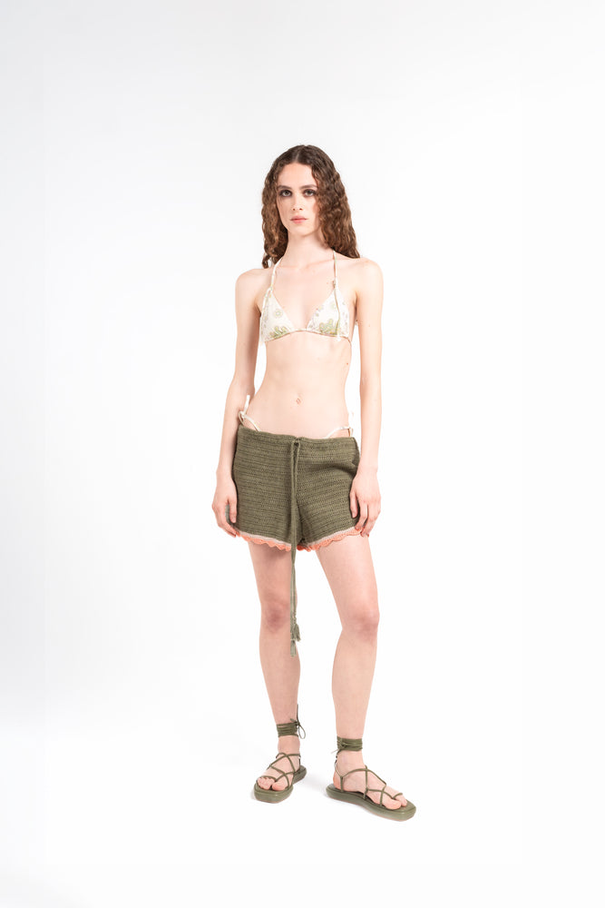 
                  
                    frontale di modella su sfondo bianco che indossa il bikini Noodle Beachwear Ellie e il pantaloncino Nala di colore verde militare dalla collezione estiva del 2025 Noodle Mirage
front of model wearing a knitted shorts miltary green called Nala from the Noodle Beachwear 2025 Noodle Mirage collection 
                  
                