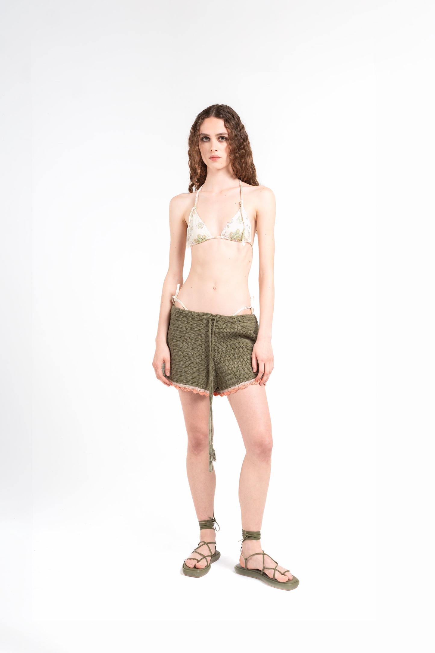 
                  
                    frontale di modella su sfondo bianco che indossa il bikini Noodle Beachwear Ellie e il pantaloncino Nala di colore verde militare dalla collezione estiva del 2025 Noodle Mirage
front of model wearing a knitted shorts miltary green called Nala from the Noodle Beachwear 2025 Noodle Mirage collection 
                  
                