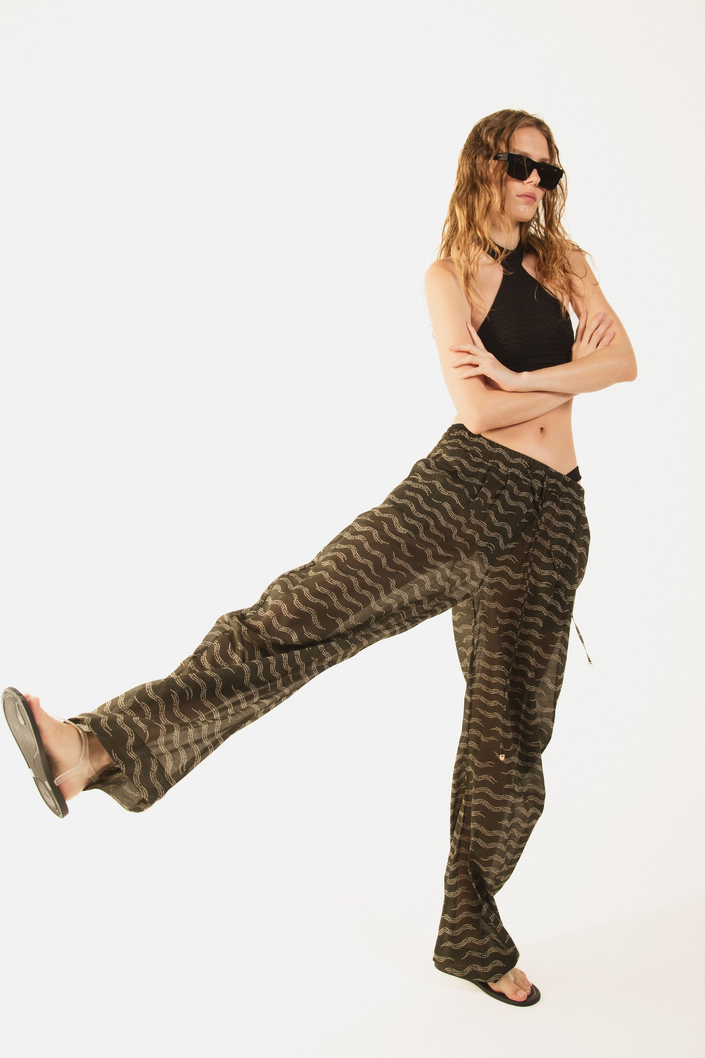 
                  
                    Girl wearing Nicasia black muslin cotton lightweighted pants with an original print wave-inspired. Premium fabrics, oversized fit. The girl wears also Cambon black bikini 
                  
                
