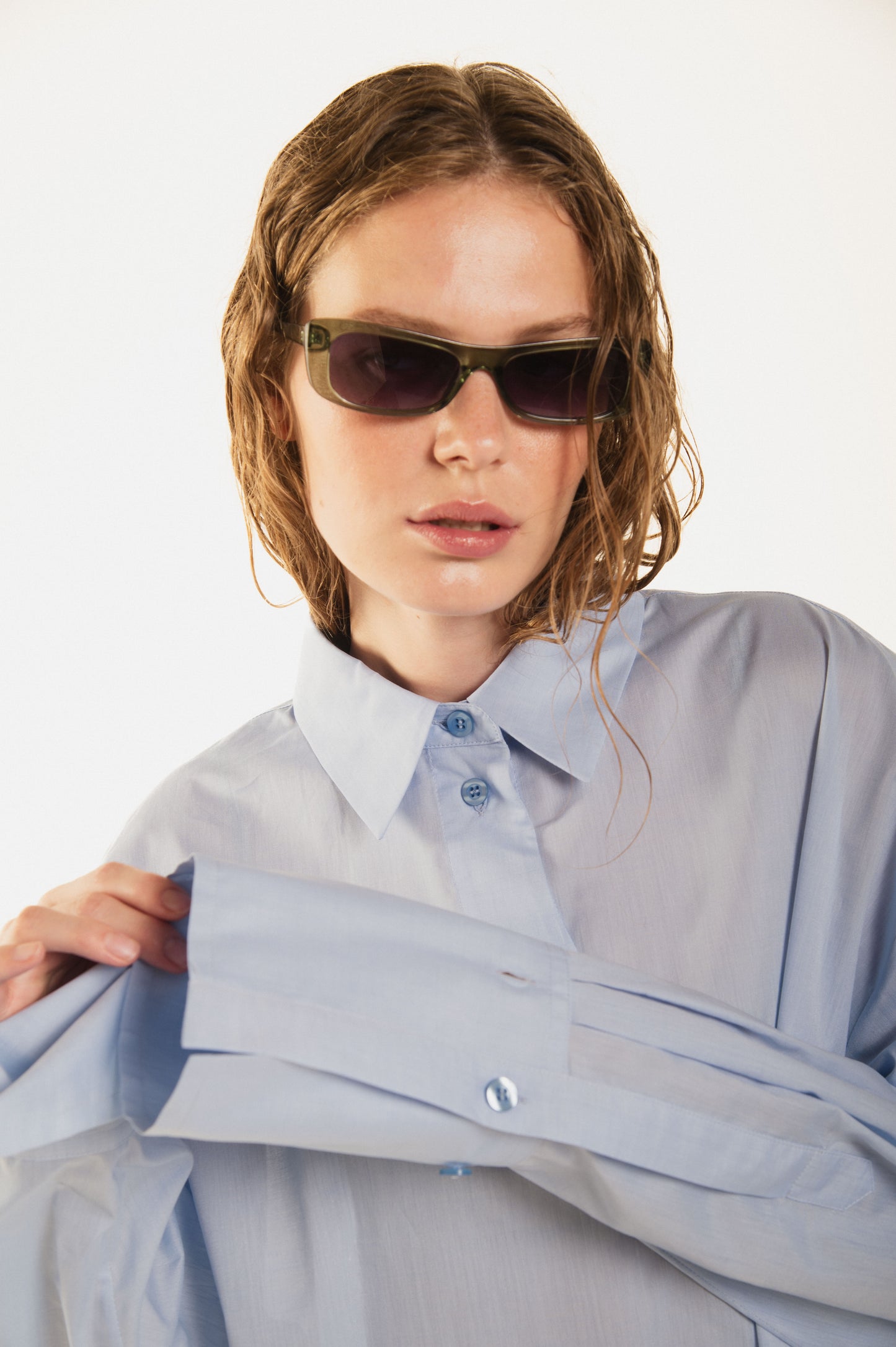 
                  
                    detail view of girl with a beautiful blue waving shirt called Terrence  premium cotton and a curved button line, oversized fit and sunglasses
                  
                