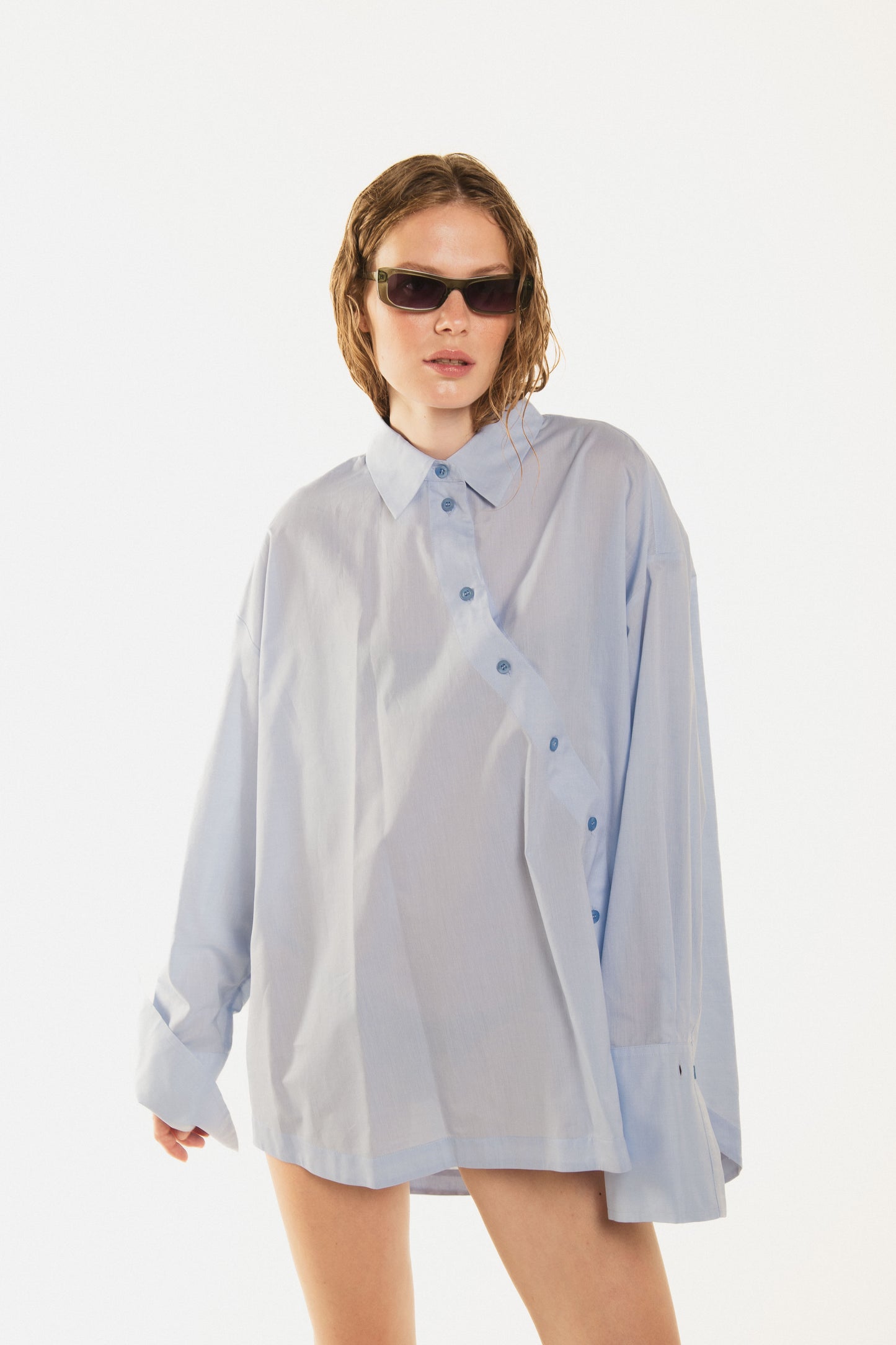 
                  
                    Front view of girl with a beautiful blue waving shirt called Terrence  premium cotton and a closed curved button line, oversized fit
                  
                