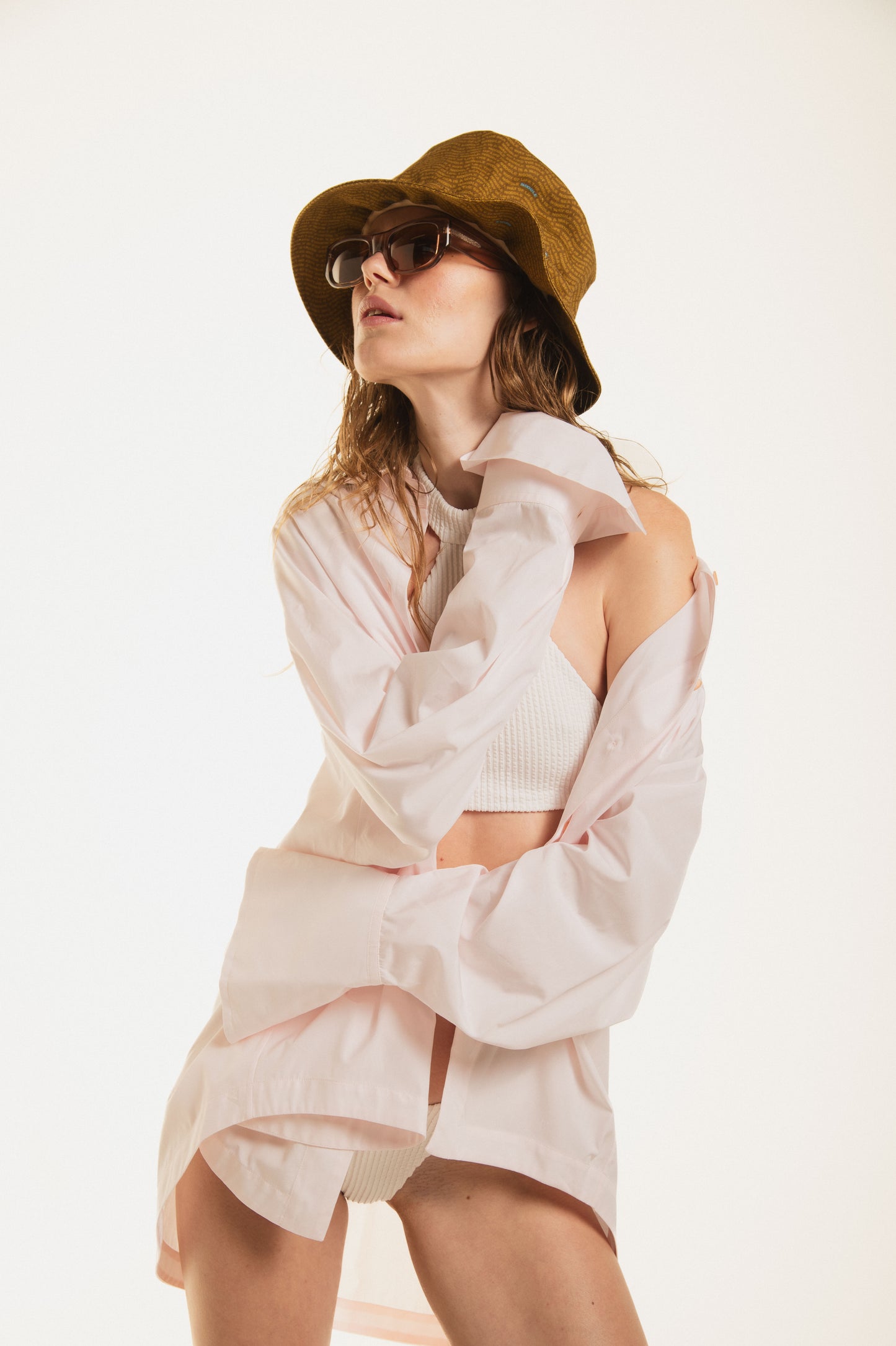 
                  
                    Pose of a girl wearing Noodle Beachwear oversize shirt in blush pink cotton with a curved row of gold jewel buttons. Maxi fit, long sleeves and effortless drape — the ultimate luxury beach cover-up. Made in Italy.
                  
                