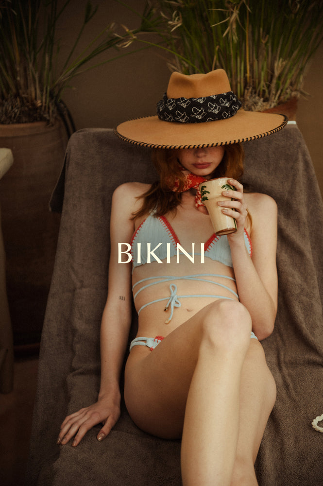 Bikini set presentation with a girl wearing a knitted bikini light blue call Lucy from the Noodle Beachwear 2025 collection called Noodle Mirage