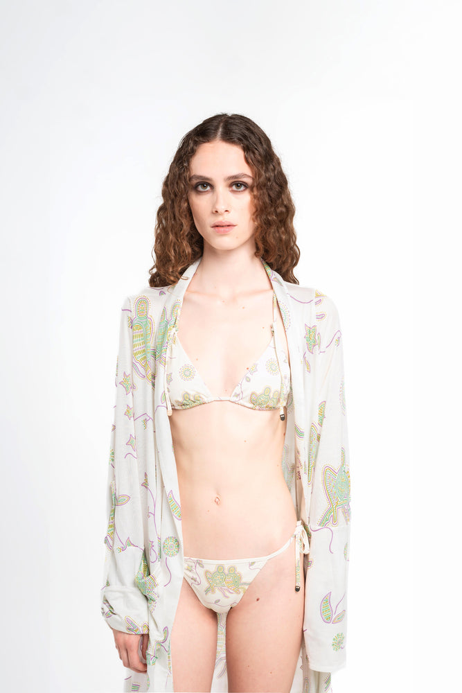 donna indossa tuyo kimono bianco latte con stampa pappagalli colorati con texture a mosaico di Noodle Beachwear dalla collezione 2025 estiva Noodle Mirage

girl wearing tuyo kimono printed whitewith print of colorful parrot and texture