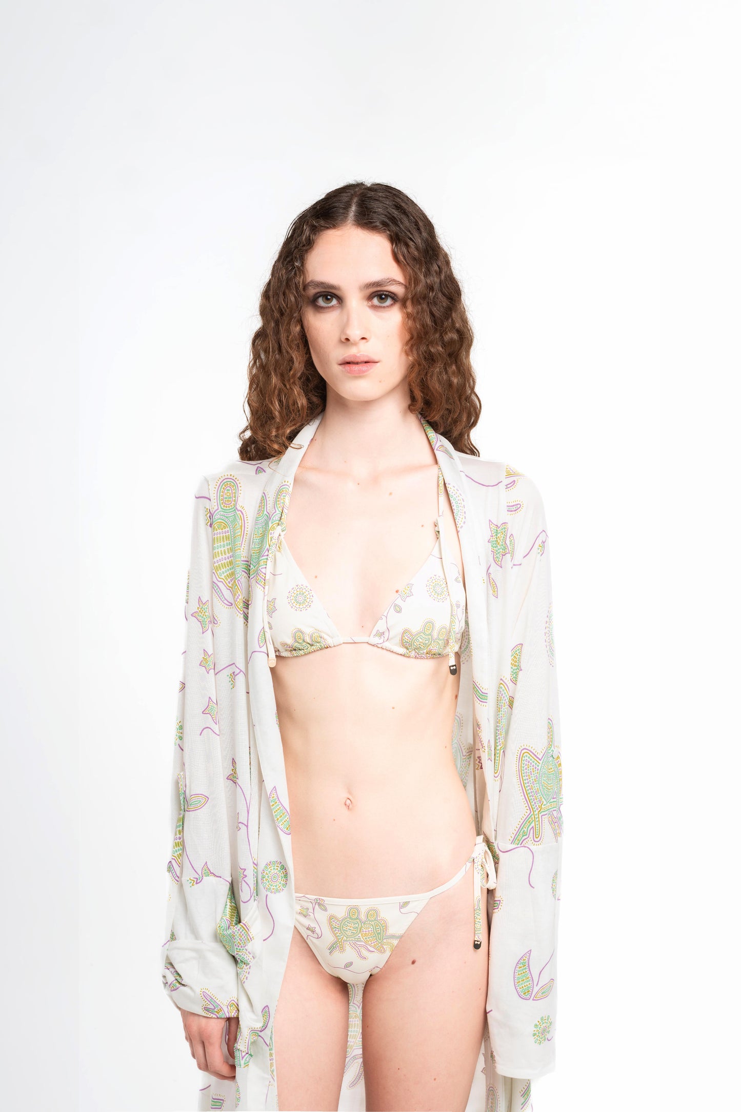 donna indossa tuyo kimono bianco latte con stampa pappagalli colorati con texture a mosaico di Noodle Beachwear dalla collezione 2025 estiva Noodle Mirage

girl wearing tuyo kimono printed whitewith print of colorful parrot and texture