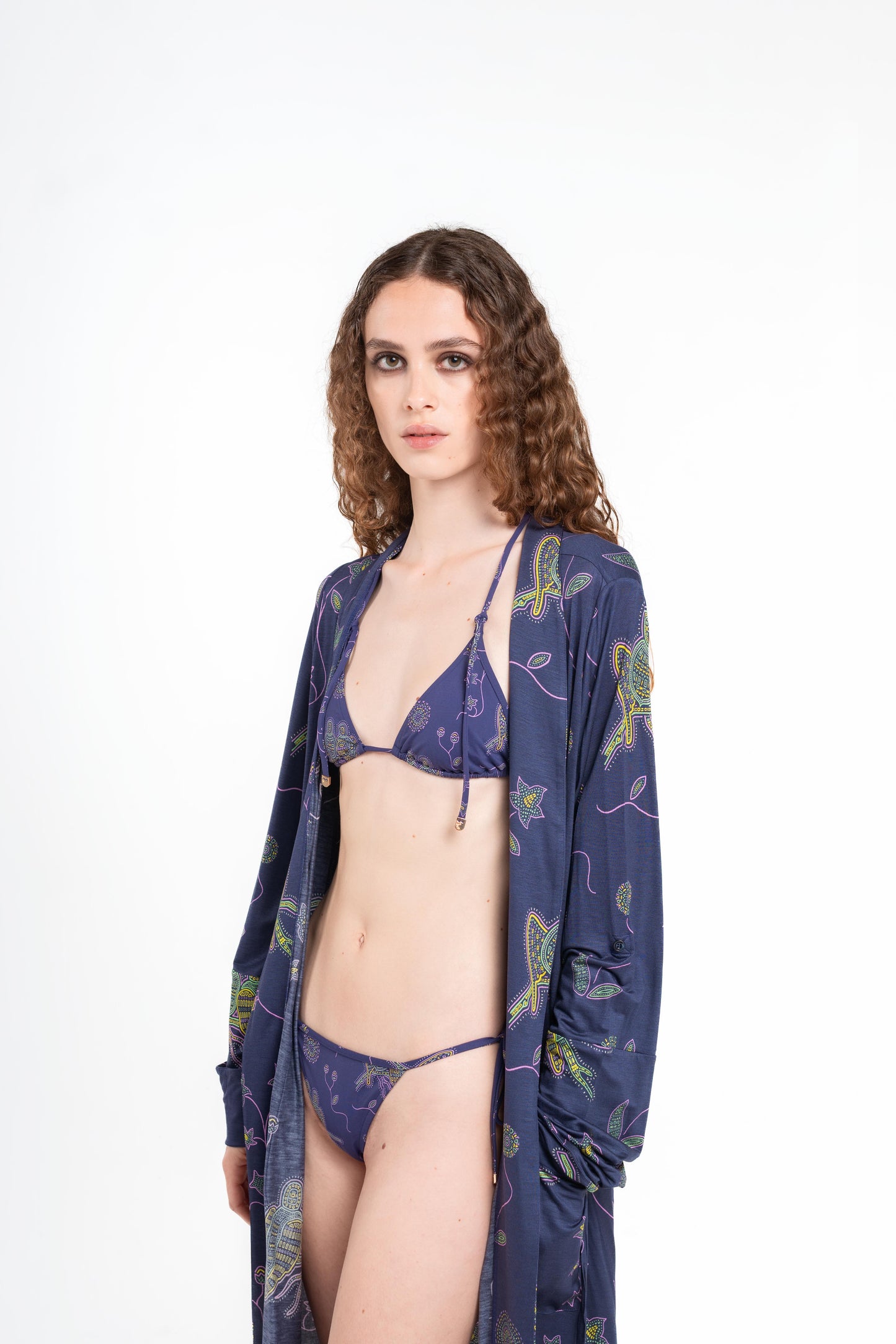 donna indossa tuyo kimono blu notte con stampa pappagalli colorati con texture a mosaico di Noodle Beachwear dalla collezione 2025 estiva Noodle Mirage

girl wearing tuyo kimono printed dark blue with print of colorful parrot and texture