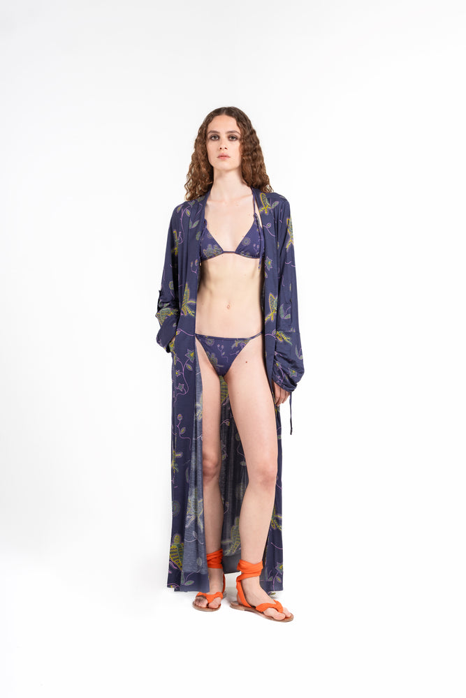 
                  
                    donna indossa tuyo lungo kimono fino alle caviglie di colore blu notte con stampa pappagalli colorati con texture a mosaico di Noodle Beachwear dalla collezione 2025 estiva Noodle Mirage

girl wearing tuyo long kimono printed dark blue with print of colorful parrot and texture
                  
                